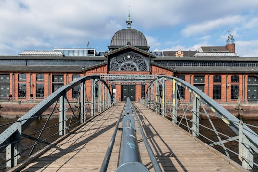pexels-photo-25922348-25922348-1 View of the historic Fish Auction Hall in Hamburg, Germany, with its iconic footbridge under a clear sky.